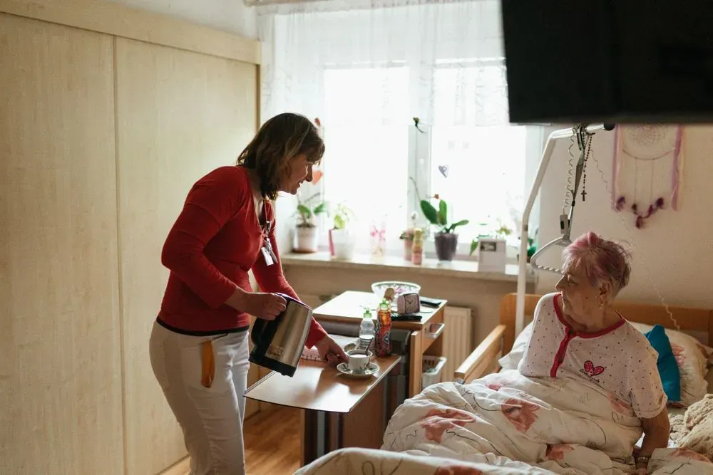 A support worker bringing tea to a client at home